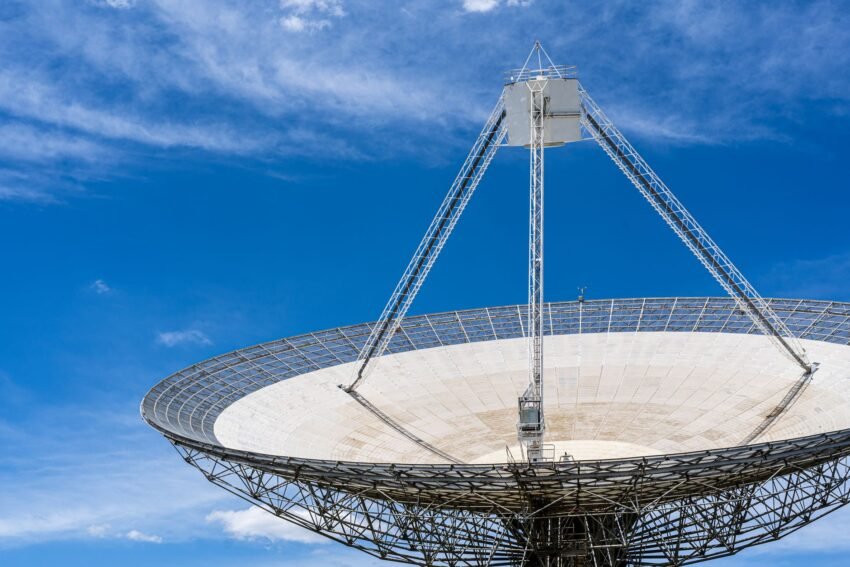 Satellite communications ground antenna beneath a blue sky.